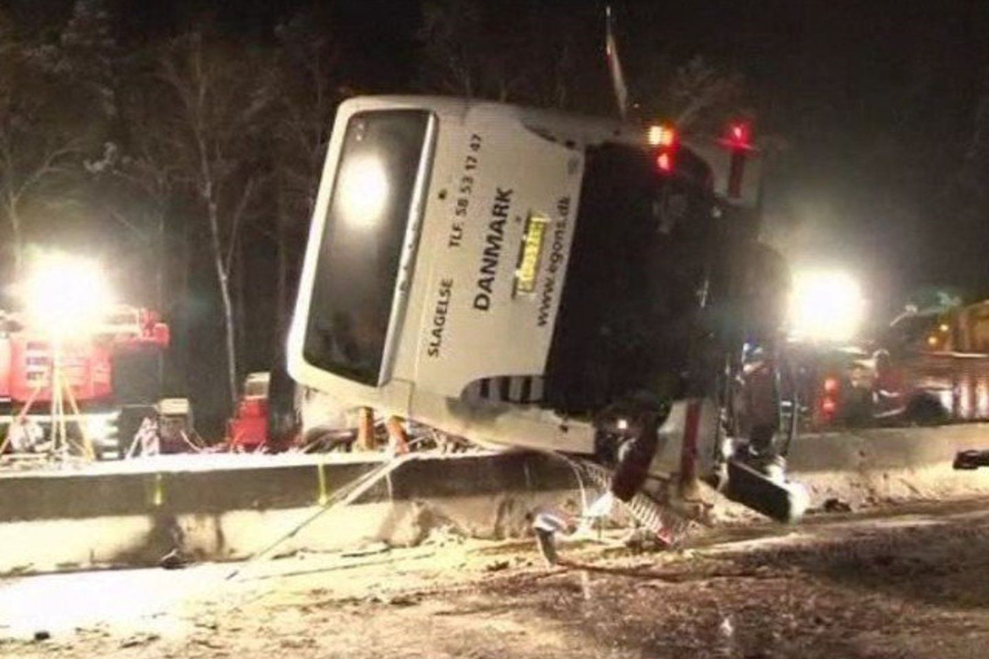 Autobusas pakibo ant apsauginės greitkelio tvoros.