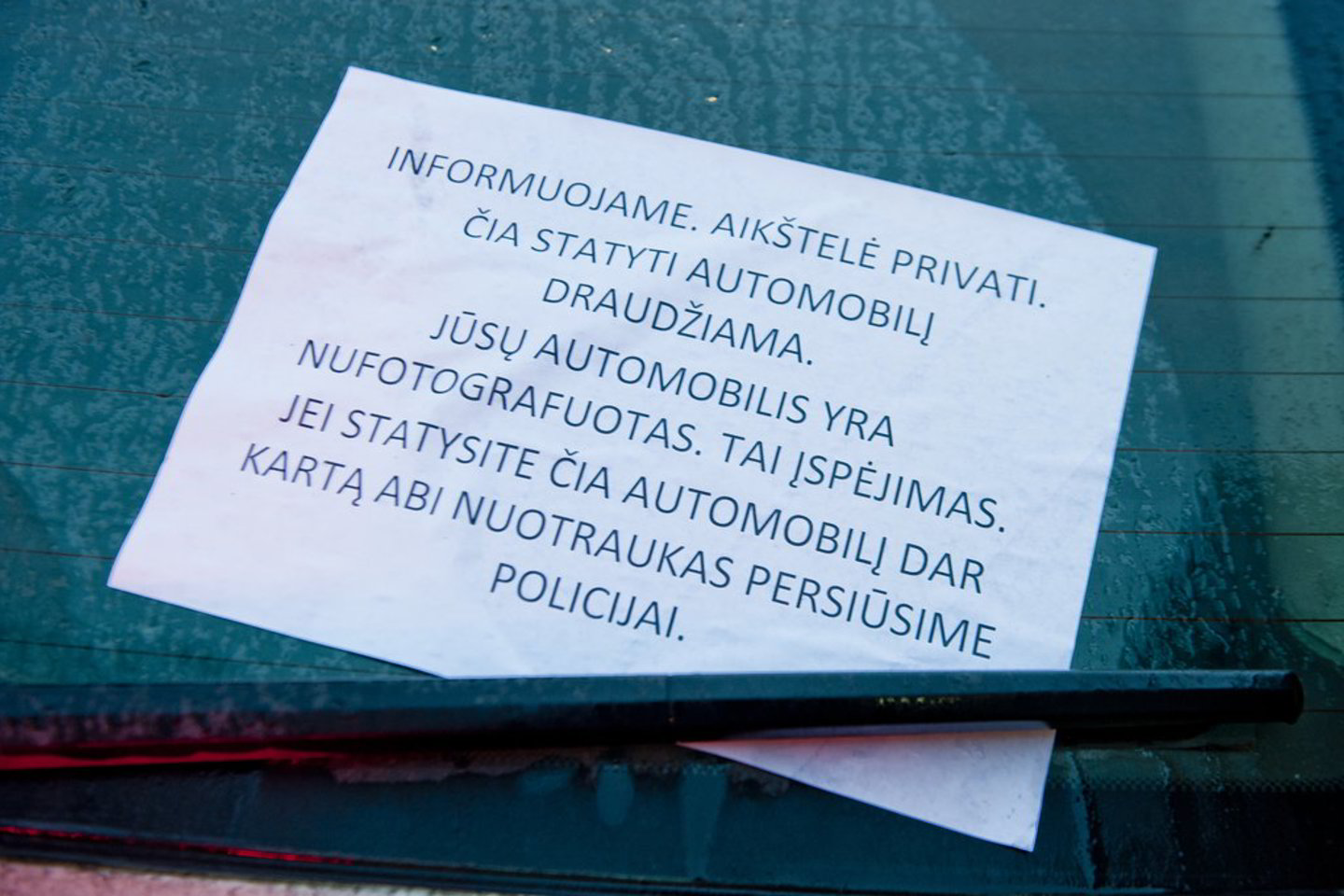 Tokį anoniminį įspėjimą vilnietė rado ant savo automobilio, kuris stovėjo aikšelėje, priklausančioje visuomeniniam pastatui ir joje nėra automobilių stovėjimą draudžiančių ženklų.