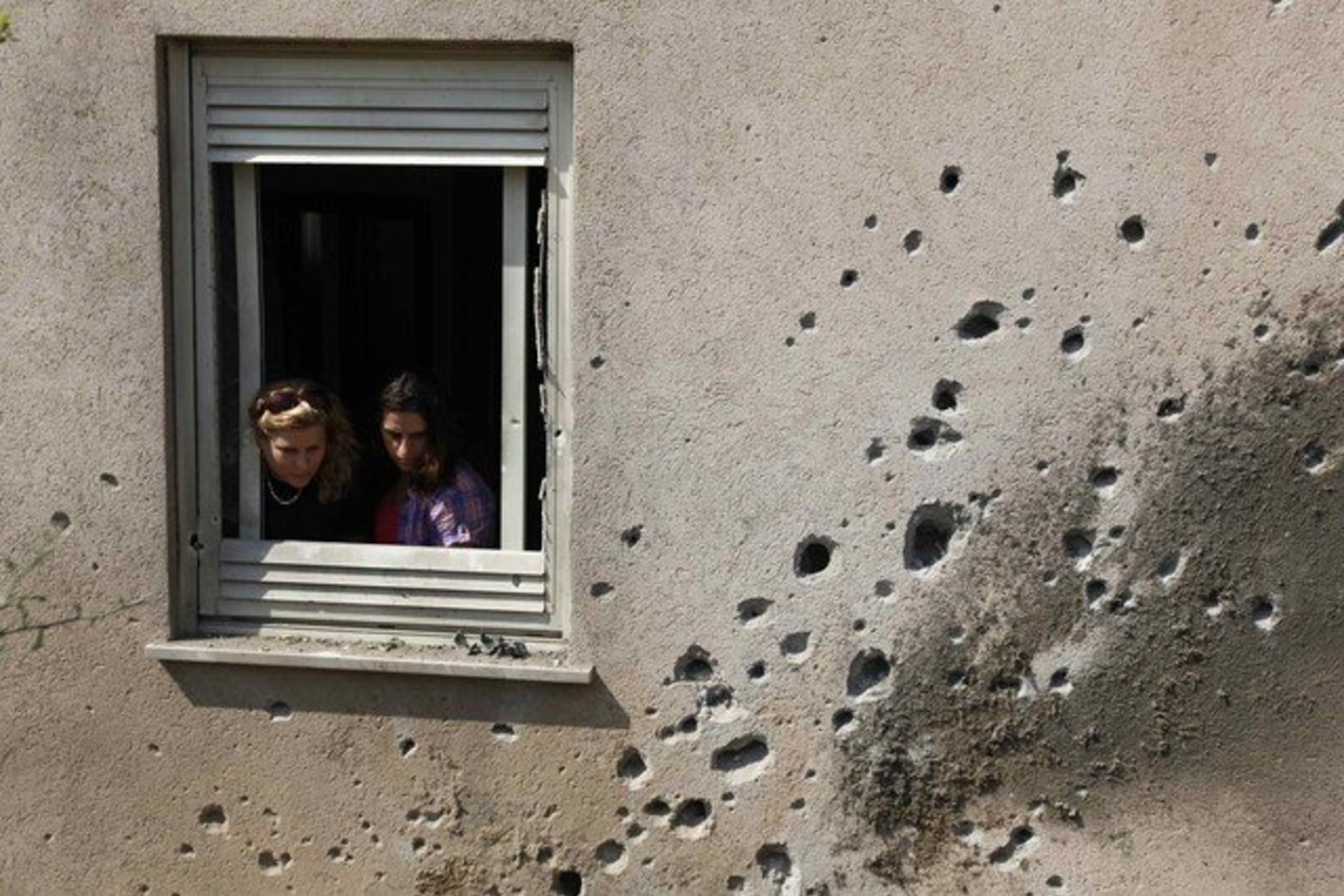 Izraelio gyventojos žiūro pro langą. Jų namą Gazos ruože apgadino raketa, paleista palestiniečių karių.