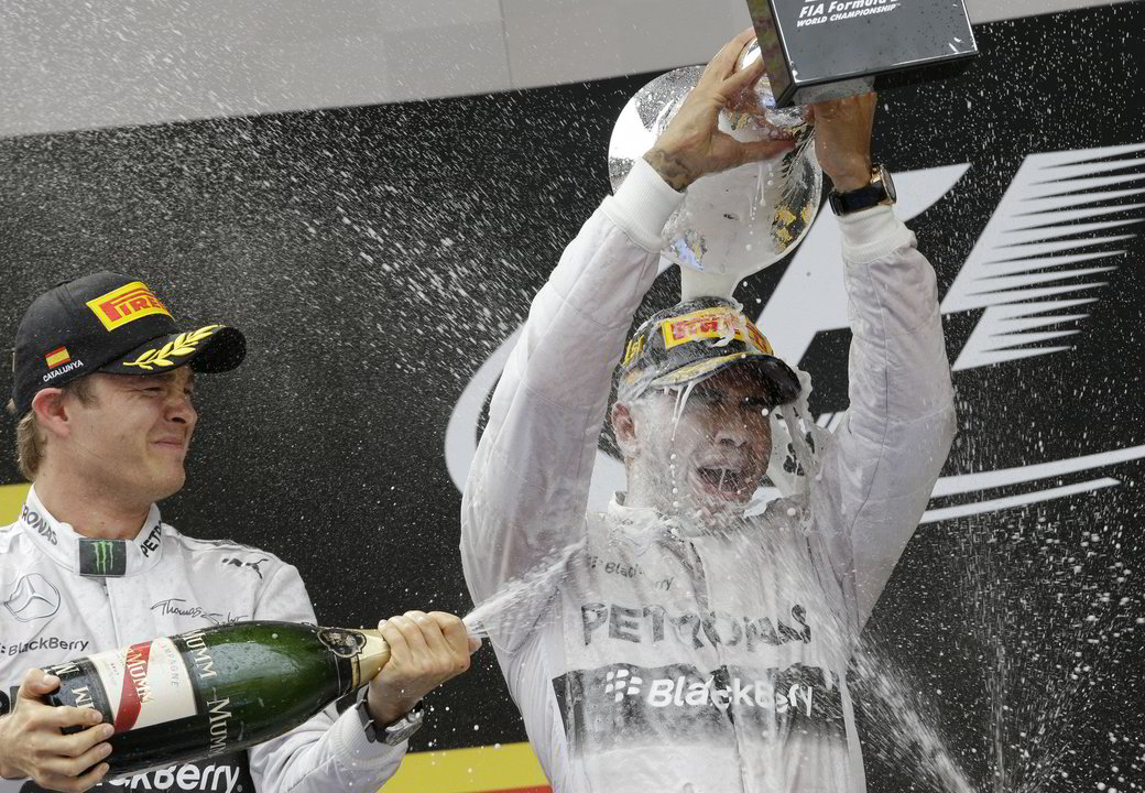 N.Rosbergas (kairėje) purškia šampaną ant L.Hamiltono.<br>AP nuotr.