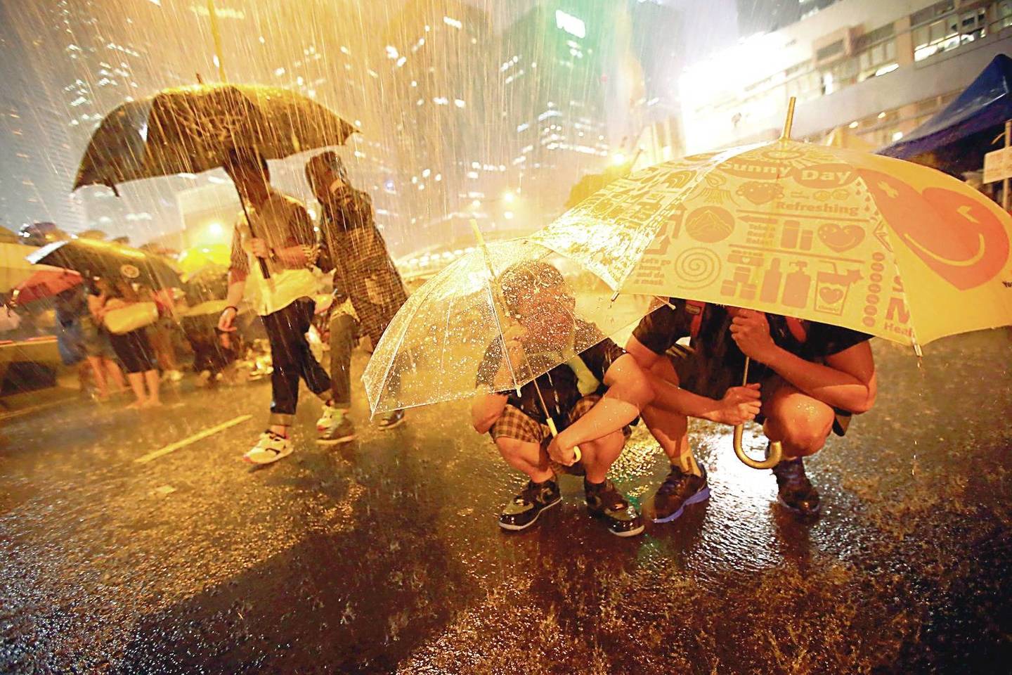 Nors dieną ir naktį besibūriuojančius protestuotojus, daugiausia studentus, nepaliaujamai merkia lietus, daugelis nesitraukia – atsinešė skėčius, kurie tapo pagrindiniu protestų simboliu.<br>AFP nuotr.
