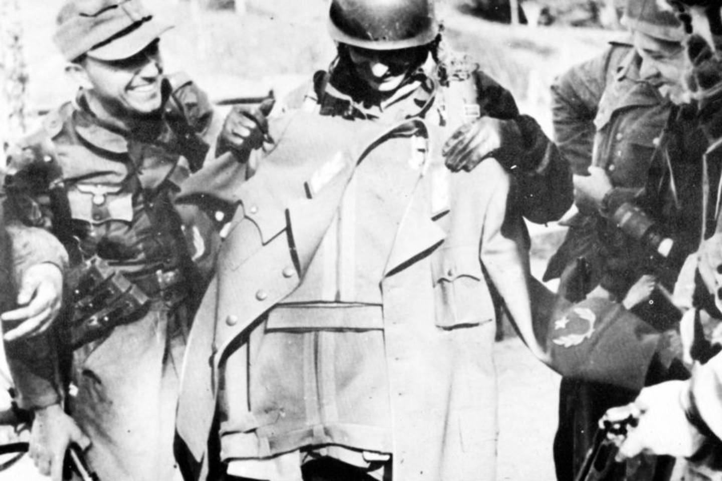 Parašiutininkai jėgeriai apžiūri naują pabėgusio partizanų vado Brozo Tito būstinėje aptiktą maršalo uniformą.<br>Iliustracija iš knygos
