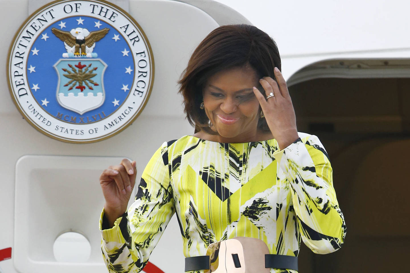 Iš JAV vyriausybės lėktuvo išlipusi M.Obama vilkėjo sodriai geltonos spalvos suknelę pūsta apačia.<br>AP nuotr.