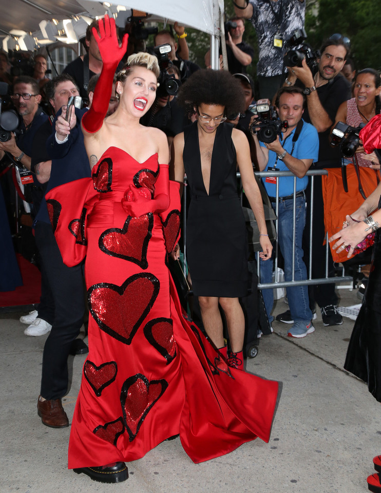 Miley Cyrus stilius: puošni suknelė, kerzai ir plaukuotos pažastys.<br>AP ir „ViDA Press“ nuotr.