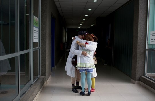 Ritualinis artistų pasikabinimas. Gydytojai klounai – nuo šiol Argentinos ligoninės privalo juos kviestis, kad pacientai geriau sveiktų.<br>AP nuotr.