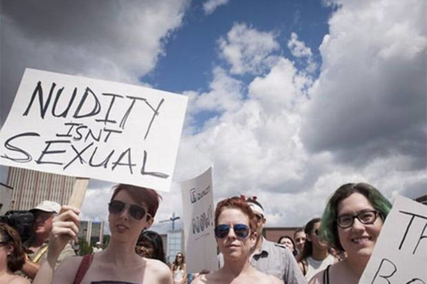 Protestuotojos laikė plakatus su užrašais: „Tai krūtys, ne bombos – nurimkit“ ir „Nuogumas nėra seksualus“.