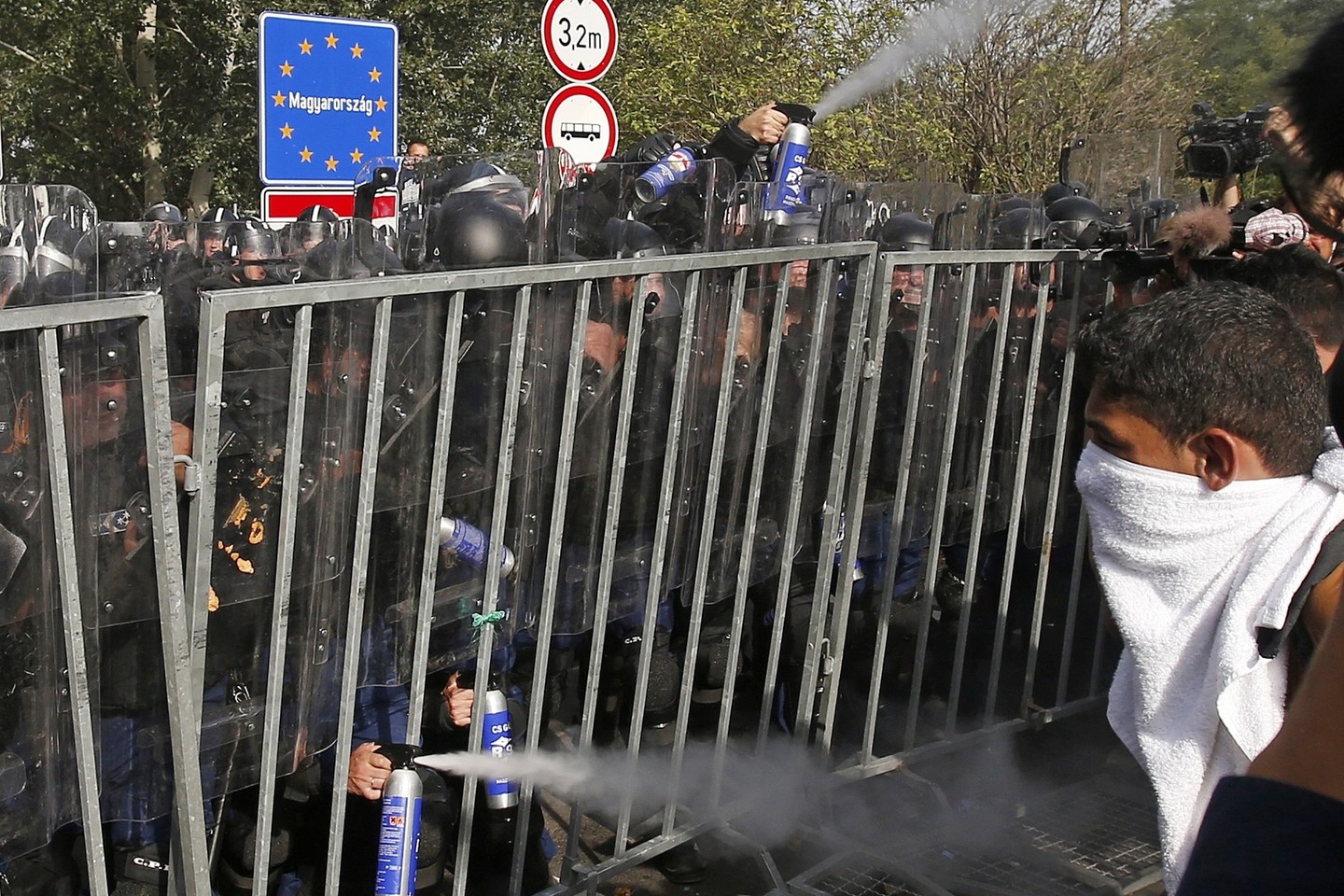 Vengrijoje – protestai: policininkai naudoja ašarines dujas, savo ruožtu pabėgėliai į juos mėto akmenis.<br>AP nuotr.