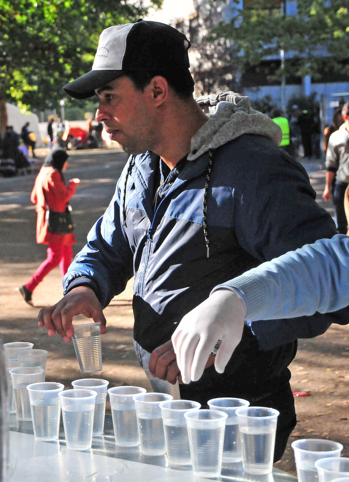 Aikštėje prie socialinės tarnybos savanoriai migrantams nemokamai dalija vandenį.<br>A.Vaitkevičiaus nuotr.