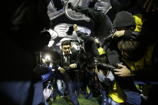 „River Plate“ treneris Marcelo Gallardo aikštę palieka saugomas riaušių policijos. Mačas su „Boca Juniors“ Agentinoje buvo sustabdytas dėl iš tribūnų į žaidėjus mėtomų pipirinių dujų.<br>AP nuotr.