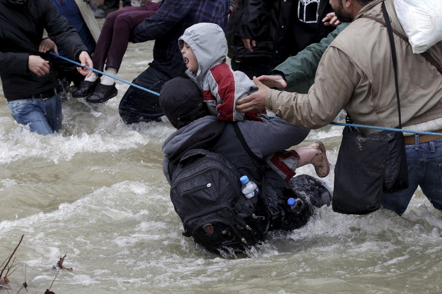 Šimtai migrantų pirmadienį perbrido upę per sieną su Makedonija.<br>„Reuters“/“Scanpix“ nuotr.