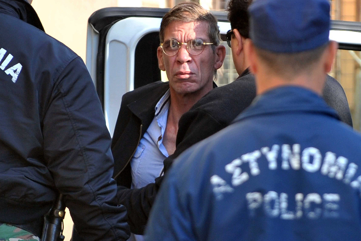 Seifas El-Dinas Mohamedas Mostafa teisme nekalbėjo. Tačiau išlipęs iš policijos automobilio jis parodė pergalės ženklą žurnalistams, susirinkusiems į posėdį, vykusį teismo rūmuose, kurie yra mažiau nei kilometro atstumu nuo Larnakos oro uosto, kur antradienį vyko įkaitų drama.<br>AFP/Scanpix nuotr.