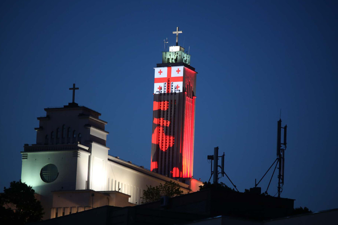 Viena Prisikėlimo bažnyčios bokšto pusių pasidabino Gruzijos vėliava.<br>M.Patašiaus nuotr.