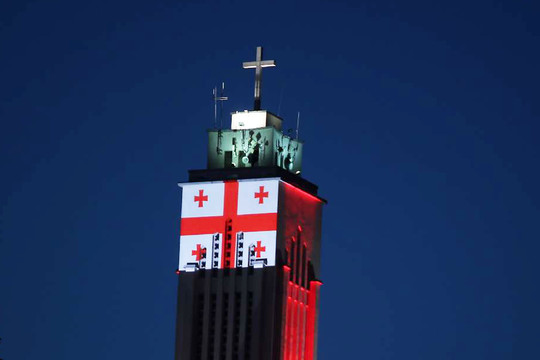 Viena Prisikėlimo bažnyčios bokšto pusių pasidabino Gruzijos vėliava.<br>M.Patašiaus nuotr.