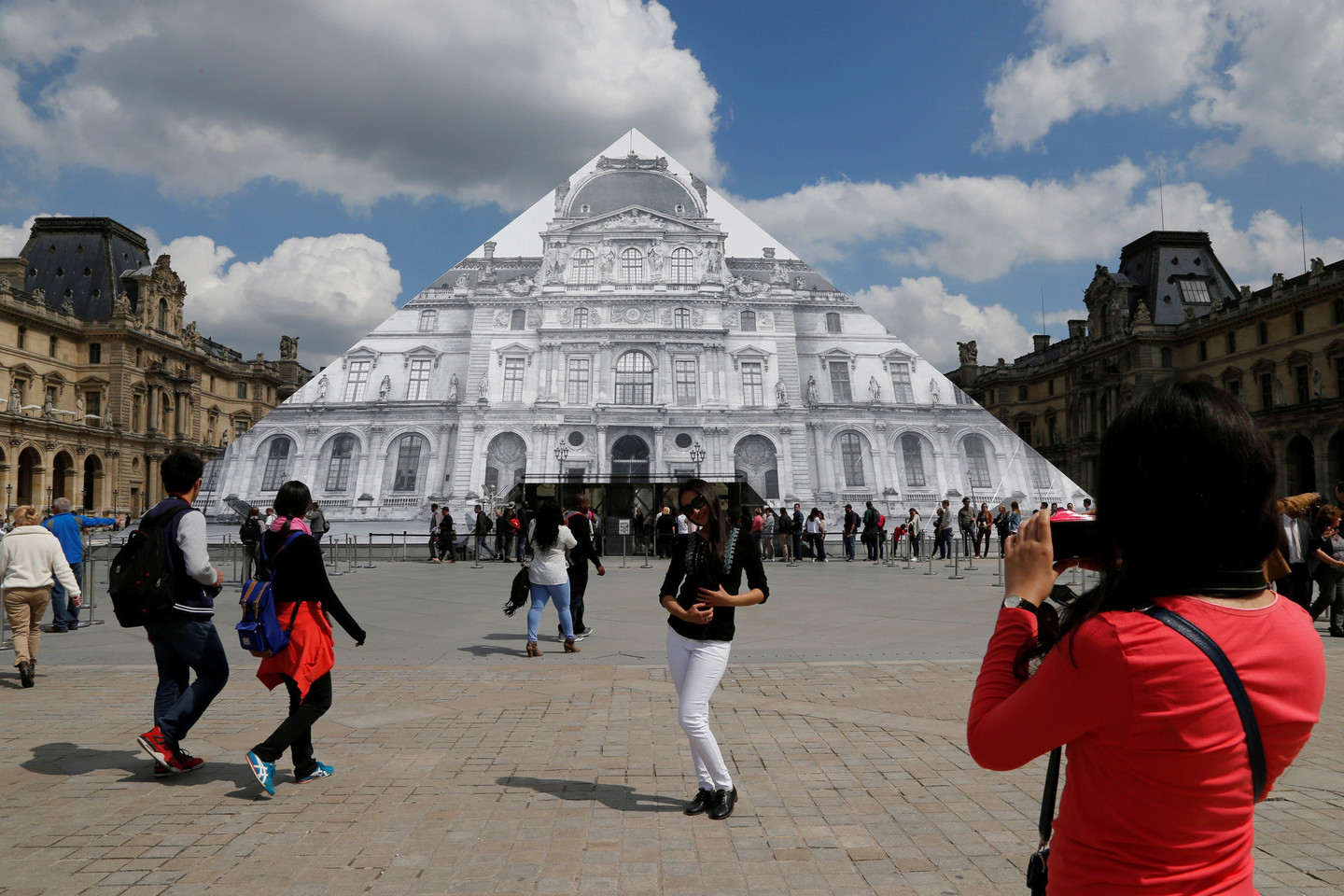 Menininkas JR uždengė Luvro piramidę didžiule nuotrauka.<br>AFP/Scanpix nuotr.