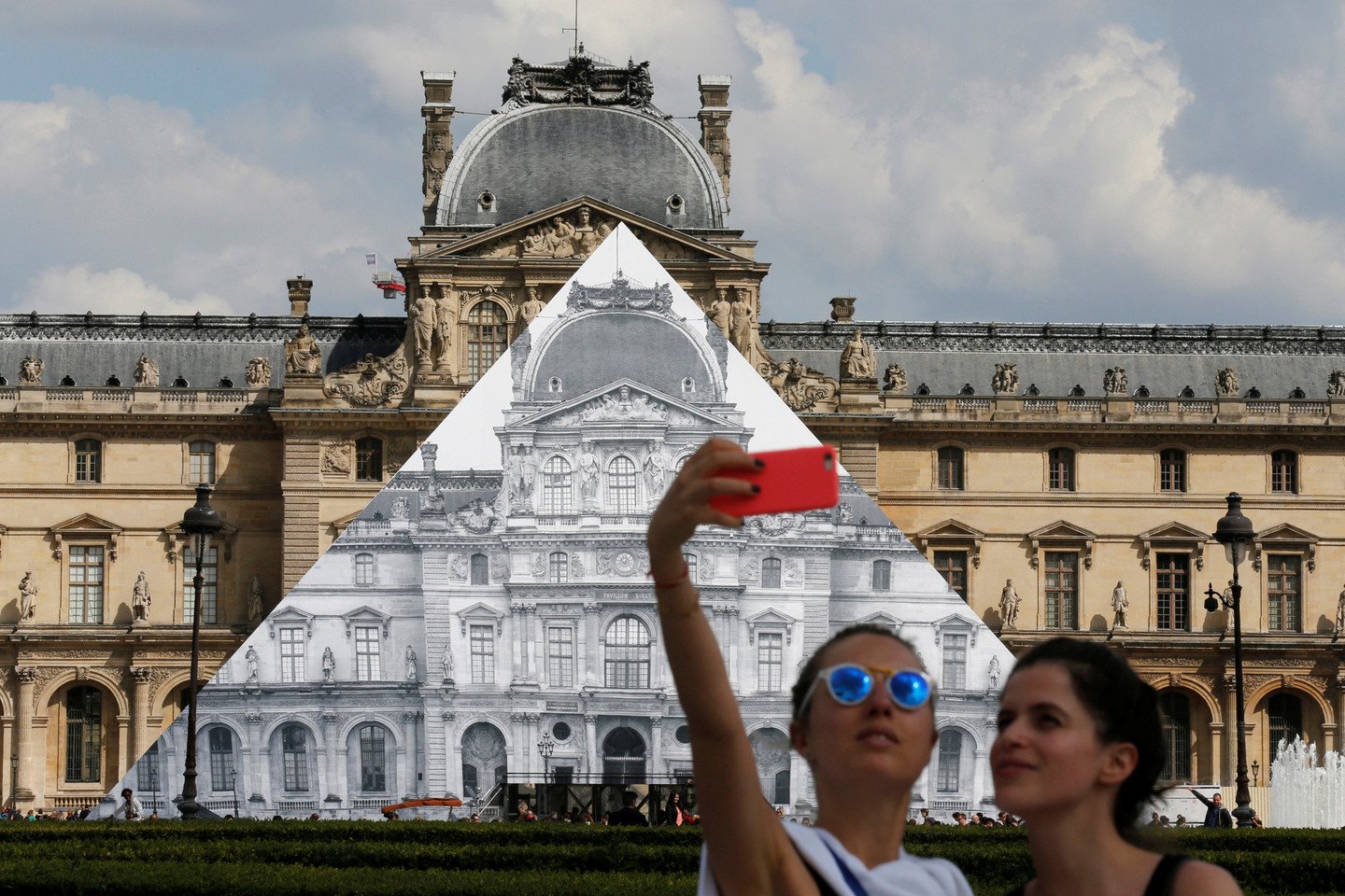 Menininkas JR uždengė Luvro piramidę didžiule nuotrauka.<br>AFP/Scanpix nuotr.