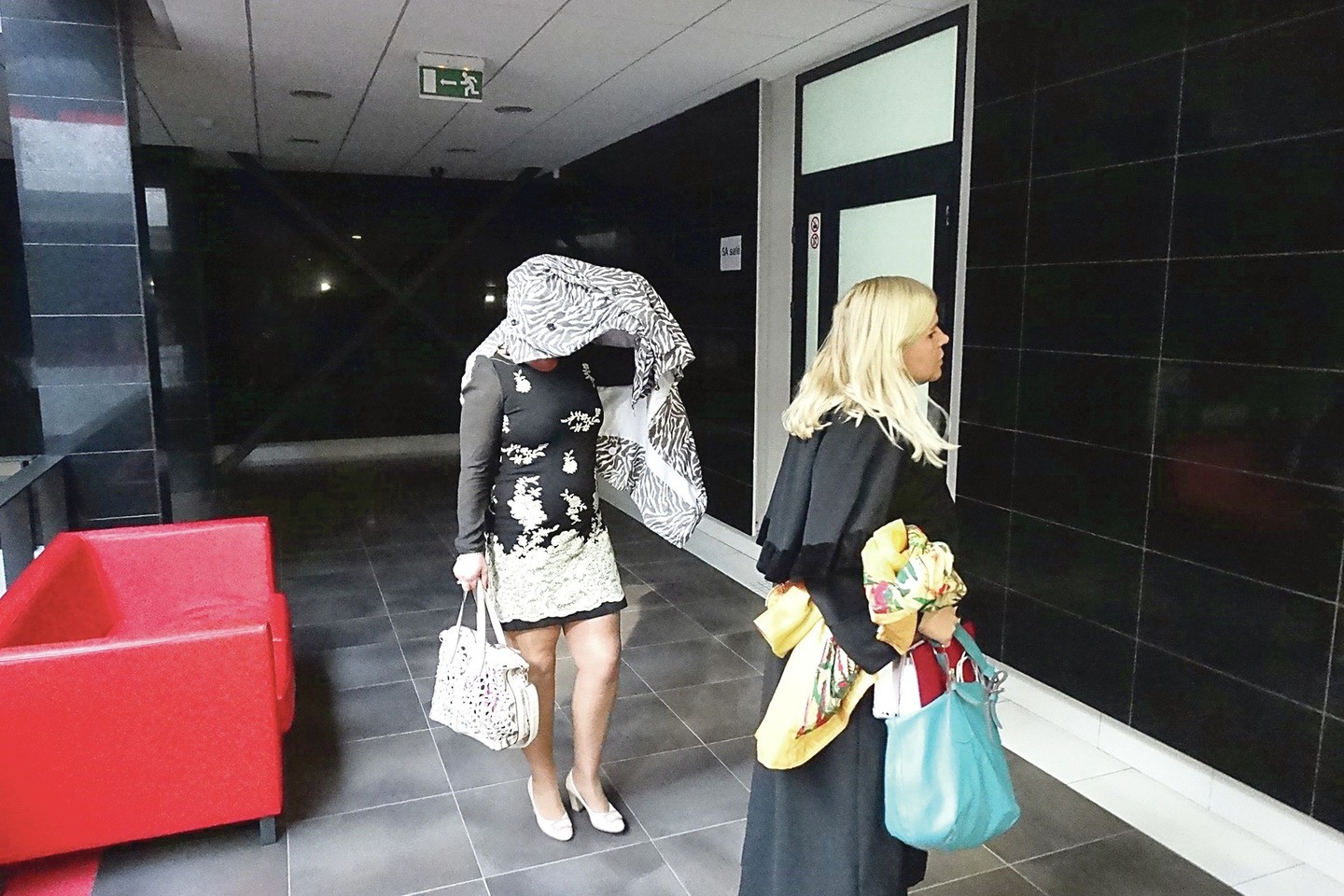 Galvą po lietpalčiu nuolat slepiančią R.Liesienę (kairėje) vakar į Kauno apygardos teismą vedė advokatė.