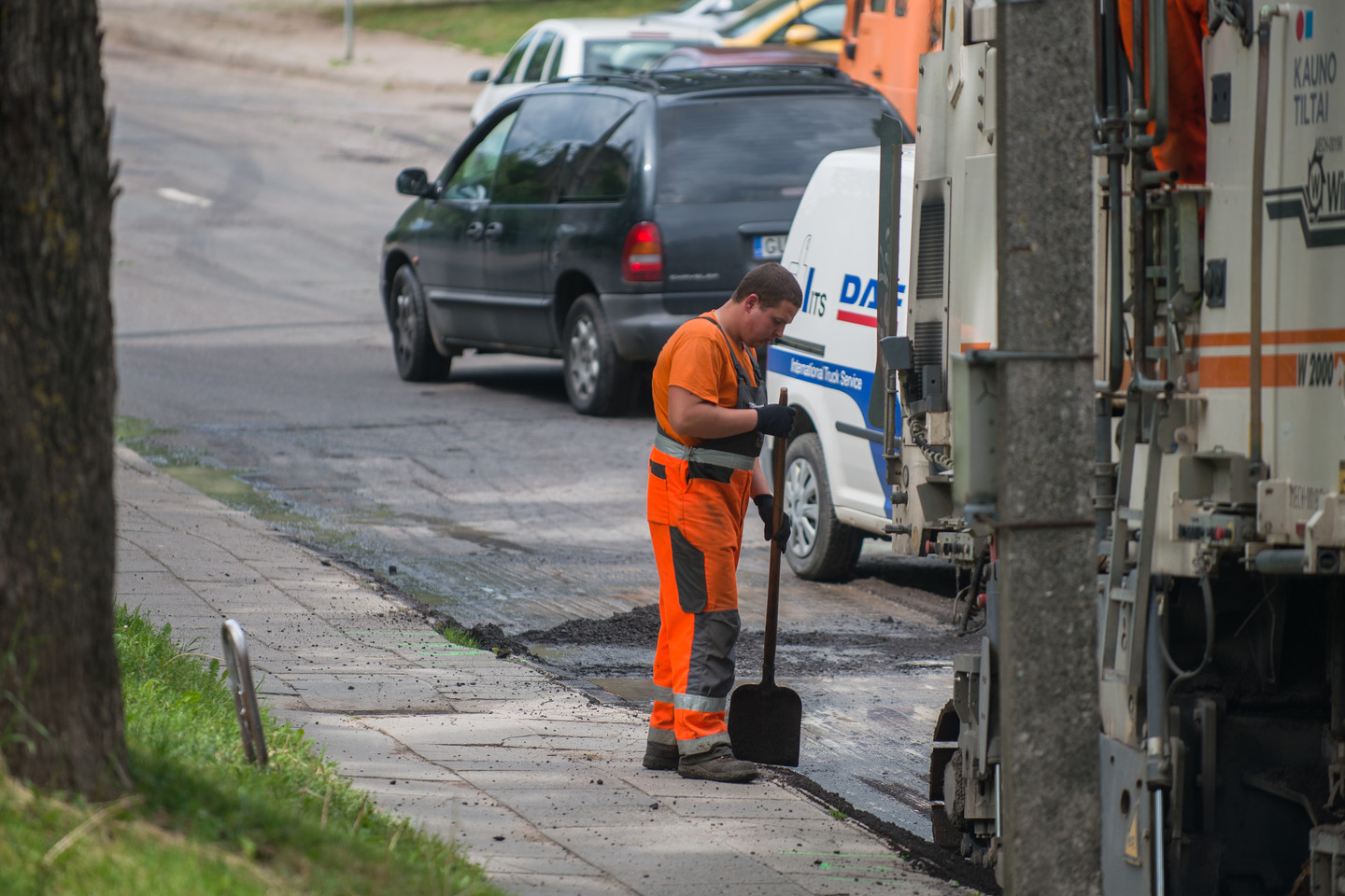  Naują asfaltą Dzūkų gatvėje darbininkai paklojo tiesiog aplink automobilius.<br> J.Stacevičiaus nuotr.