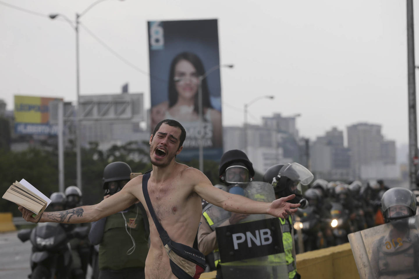  Vyras su Biblija gatvės riaušėse su policija. Balandžio 20 d., Karakasas (Venesuela).<br> AP nuotr.