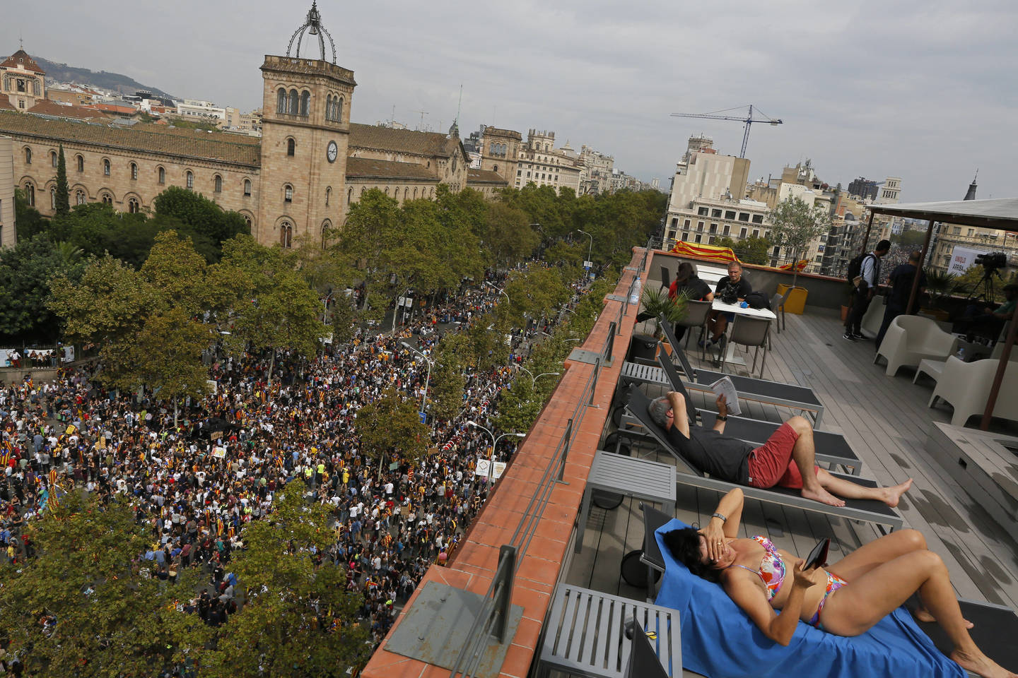  Turistai deginasi ant viešbučio stogo, o gatvėje vyksta Katalonijos nepriklausomybės šalininkų demonstracija. Spalio 3 d., Barselona (Ispanija).<br> AP nuotr.