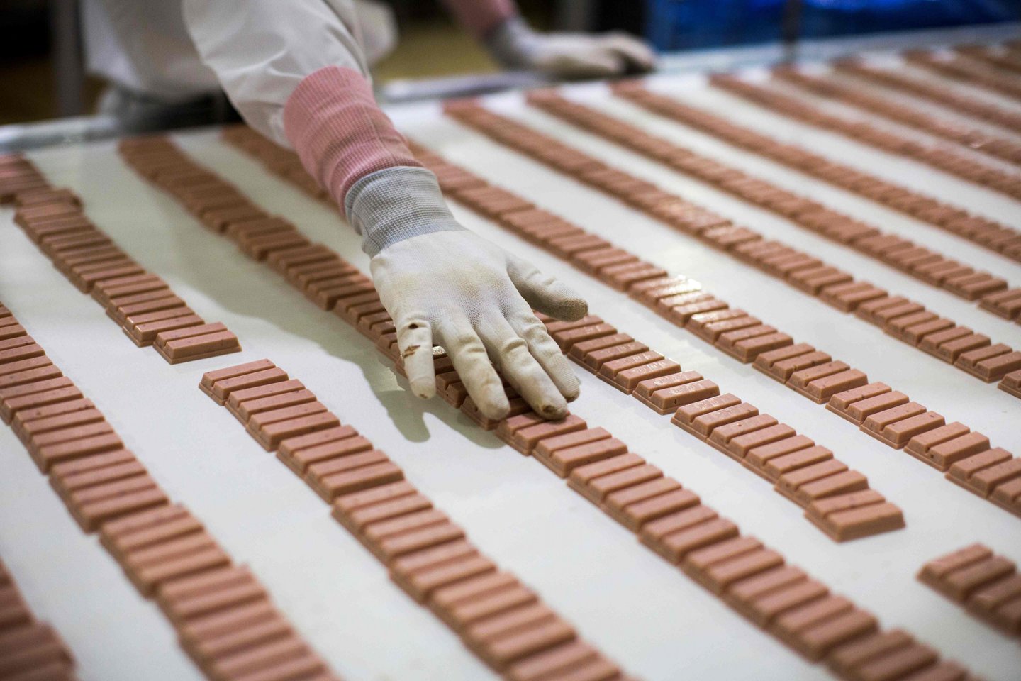 Darbuotojas Japonijoje tikrina braškių skonio „KitKat“ saldumynus.<br>AFP/Scanpix nuotr.