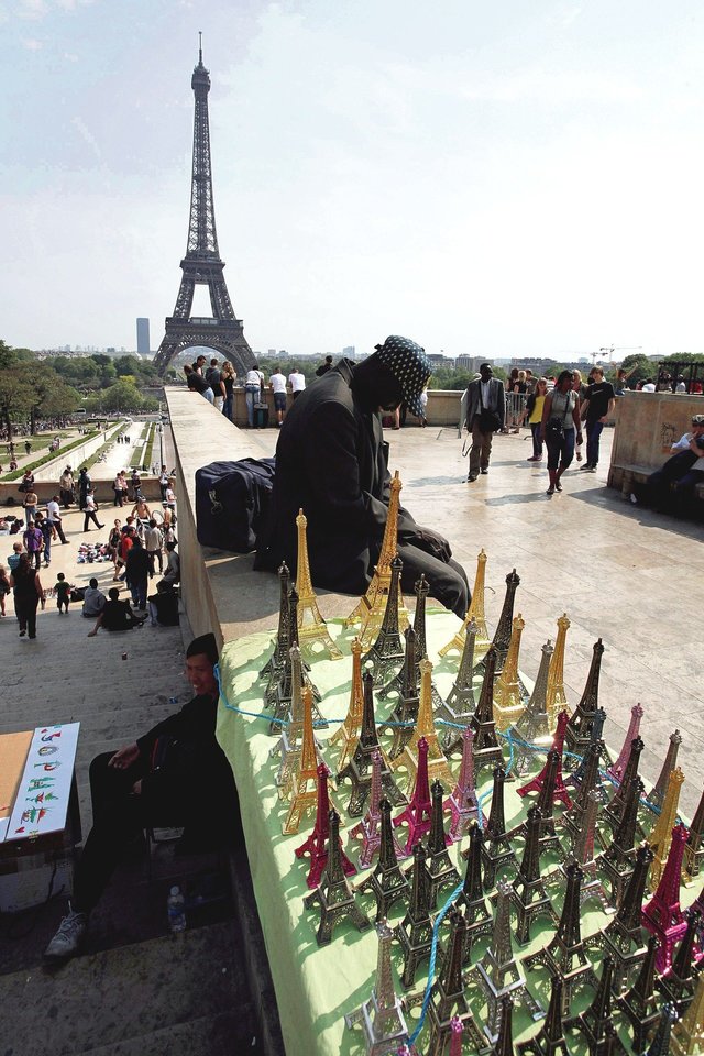 Suvenyrus nelegalūs prekeiviai siūlo Paryžiaus turistinėse vietose.<br>„Reuters“/„Scanpix“ nuotr.