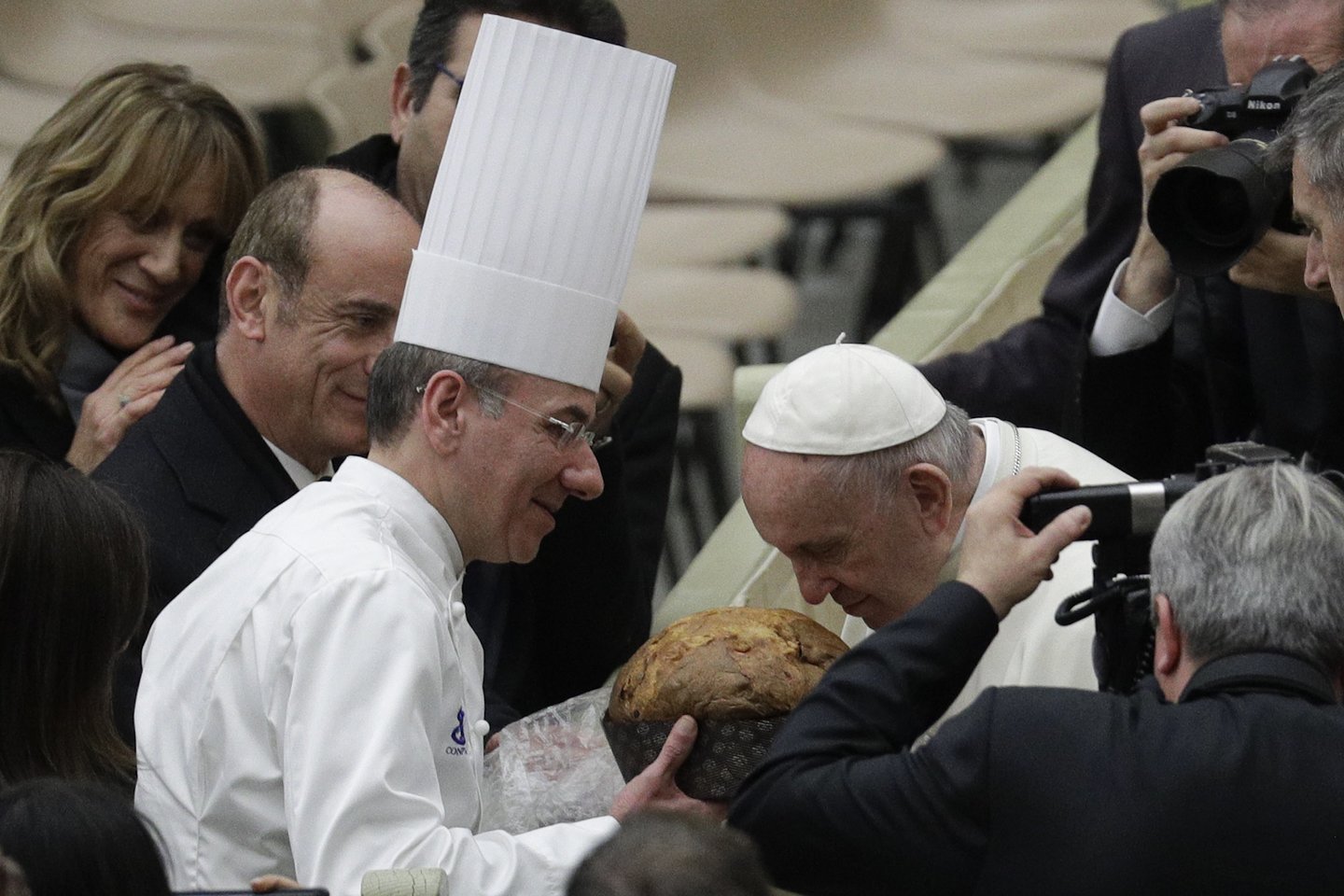  Popiežius Pranciškus uosto tradicinį Kalėdų pyragą Panettone.<br> AP nuotr.