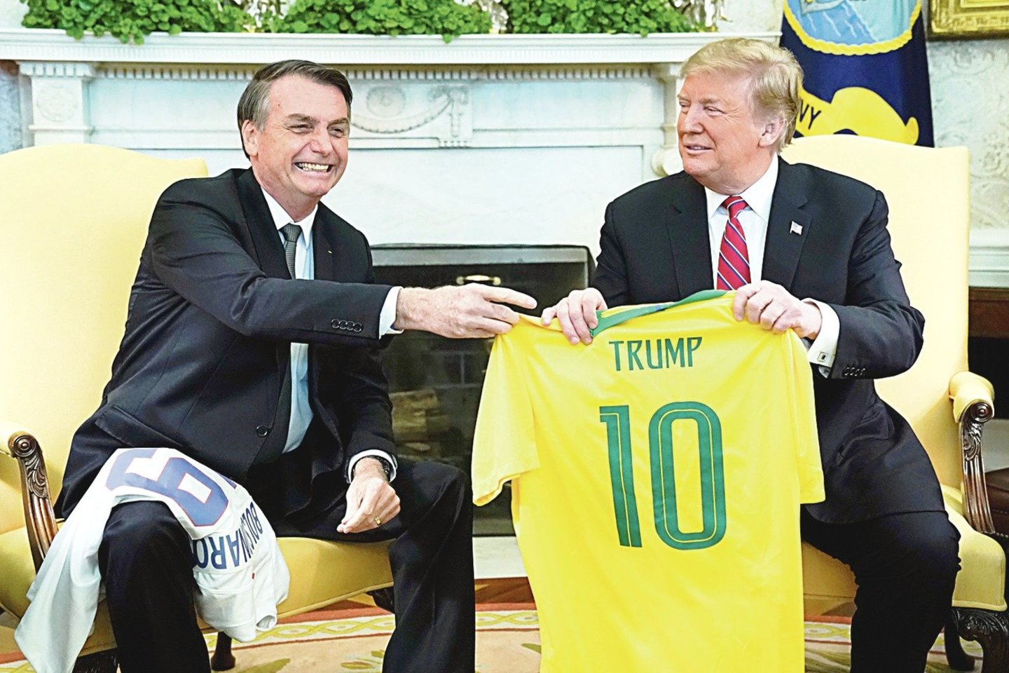 Susitikę JAV prezidentas D.Trumpas (dešinėje) ir Brazilijos vadovas J.Bolsonaro pasikeitė futbolo marškinėliais su šalių simbolika ir vienas kito pavardėmis.<br>„Reuters“/„Scanpix“ nuotr.