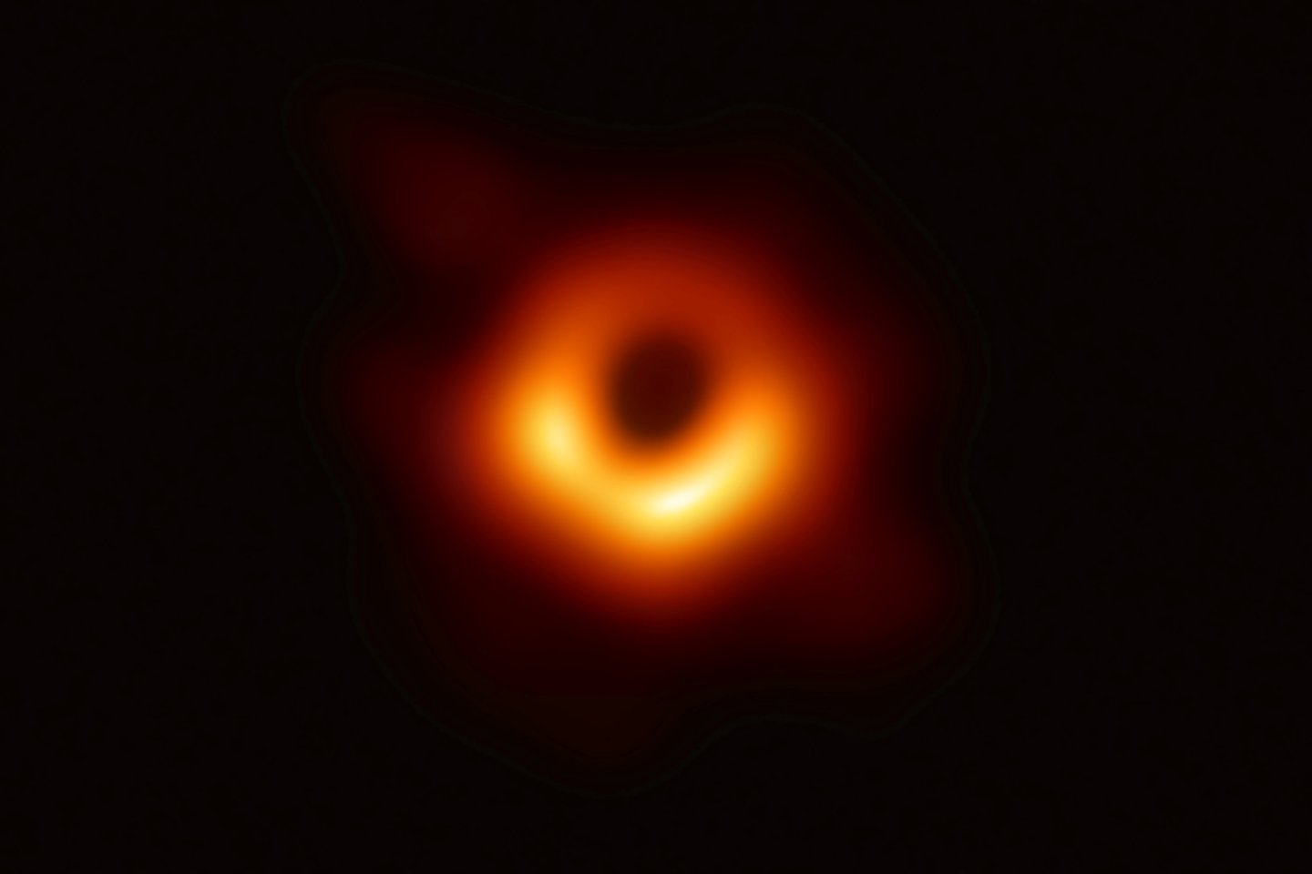   Tamsus apskritimas centre yra juodosios skylės šešėlis, ribojamas šviesių dujų, gaubiančių skylę ir į ją krentančių.<br> Reuters / Scanpix nuotr.