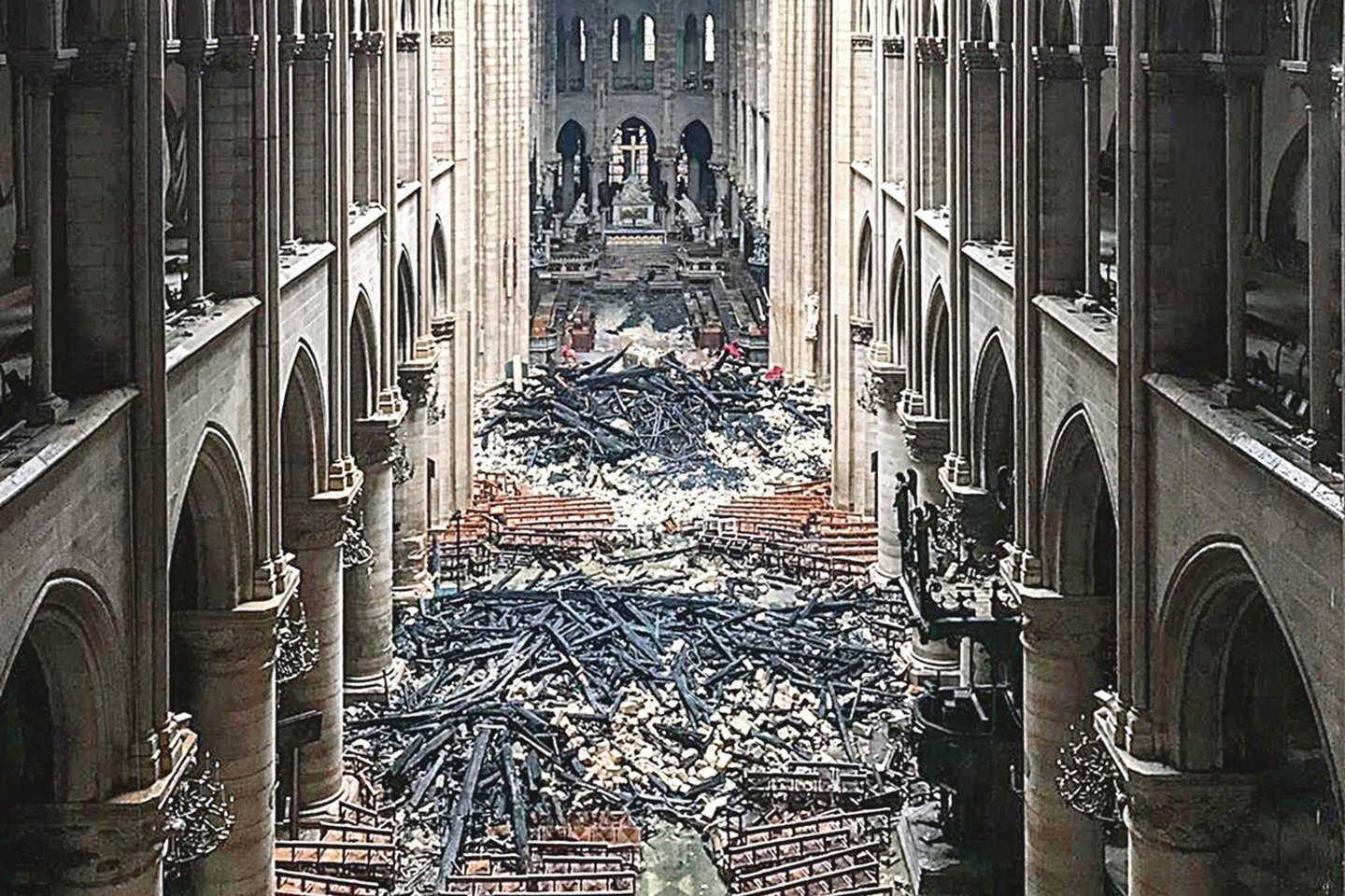 Paryžiaus Dievo Motinos katedros viduje – įgriuvęs sudegęs stogas ir suolai.
