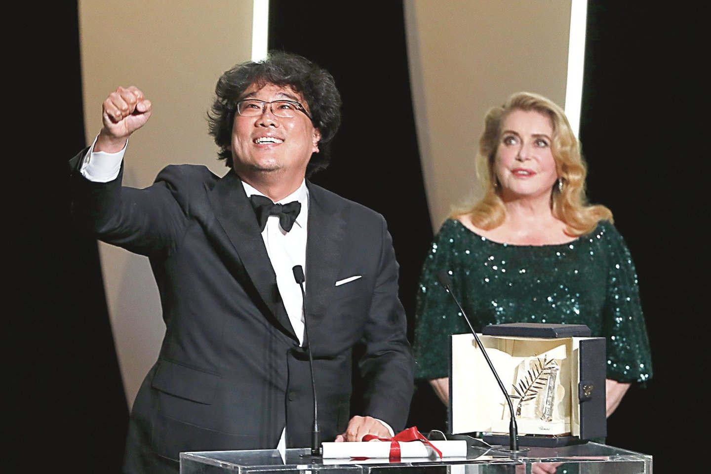 Auksinę palmės šakelę Pietų Korėjos režisieriui Bong Joon-ho Kanuose įteikė prancūzų garsenybė C.Deneuve.<br>„Scanpix“ nuotr.