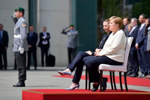 Po drebulio priepuolių A. Merkel skambant nacionaliniams himnams liko sėdėti