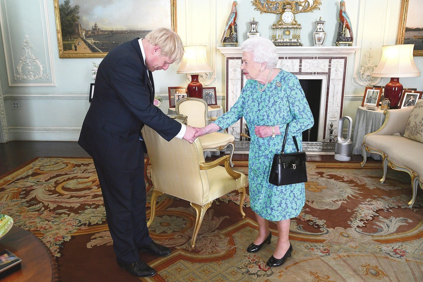 Karalienė Elizabeth II išlydėjo buvusią premjerę ir pasitiko naująjį – B.Johnsoną juokaudama ir atsipalaidavusi.<br>„Reuters“/„Scanpix“ nuotr.