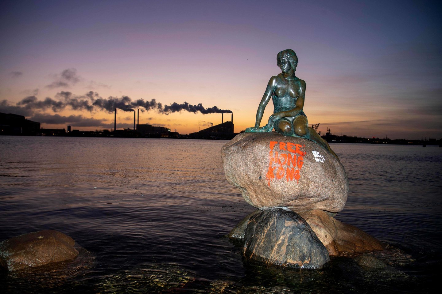  Danijos sostinės simboliu tapusi garsioji „Undinėlės“ skulptūra buvo išpaišyta grafičiais – Honkongą palaikančiais šūkiais.<br> AFP/Scanpix nuotr.