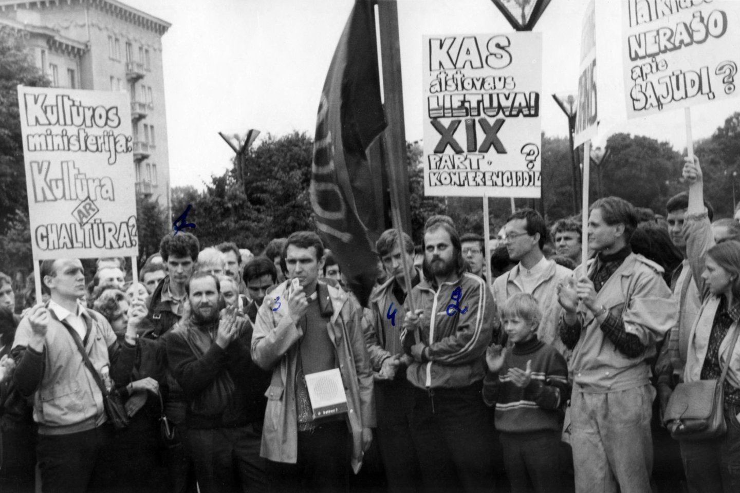 Pirmasis Sąjūdžio mitingas prie LSSR Aukščiausiosios Tarybos rūmų. Greta pirmu numeriu paženklinto Arūno Degučio pavardės kitoje nuotraukos pusėje pažymėta, kad jis jau žinomas KGB darbuotojams kaip „nacionalistas“.