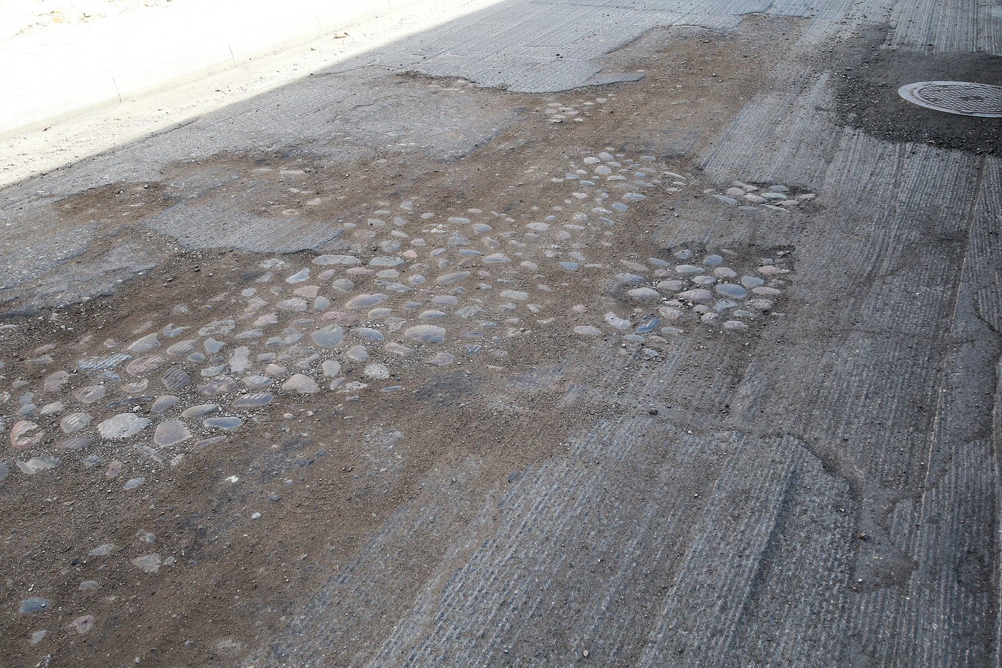 Subačiaus gatvės atkarpą nugremžus frezomis pasirodė senojo grindinio akmenys. Bet tai savivaldybės nesudomino – jie bus kuo greičiau užlieti asfaltu.<br>R.Danisevičiaus nuotr.