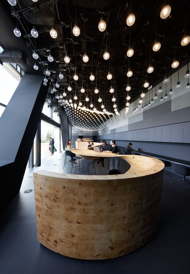 Bendradarbystės erdvė Tokijuje, kurią Norvegijoje įsikūręs architektų biuras „Snohetta“ suprojektavo japonų technologijų įmonei „Digital Garage“, išsiskiria ypatinga detale – per biurą besitęsiančiais stalviršiais, primenančiais didžiules medines juostas.<br>Nacasa &amp; Partners / snohetta nuotr.