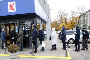 Pasikeitus tvarkai prie parduotuvių ir vaistinių durų – eilės: lietui lyjant žmonės glaudžiasi vienas šalia kito po stogeliu