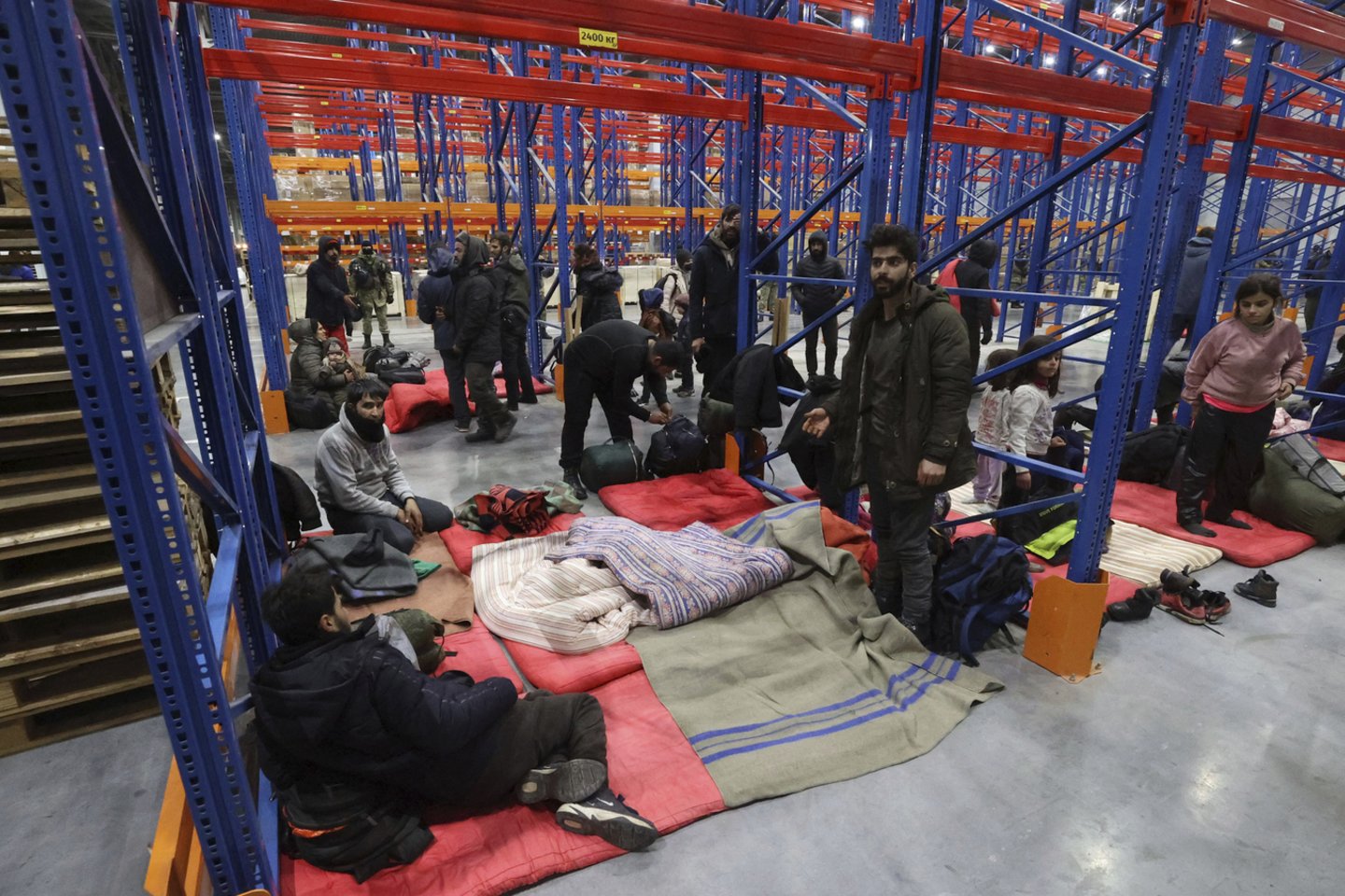 Migrantai, apsistoję netoli sienos esančiame logistikos centre.<br>AP/Scanpix nuotr.