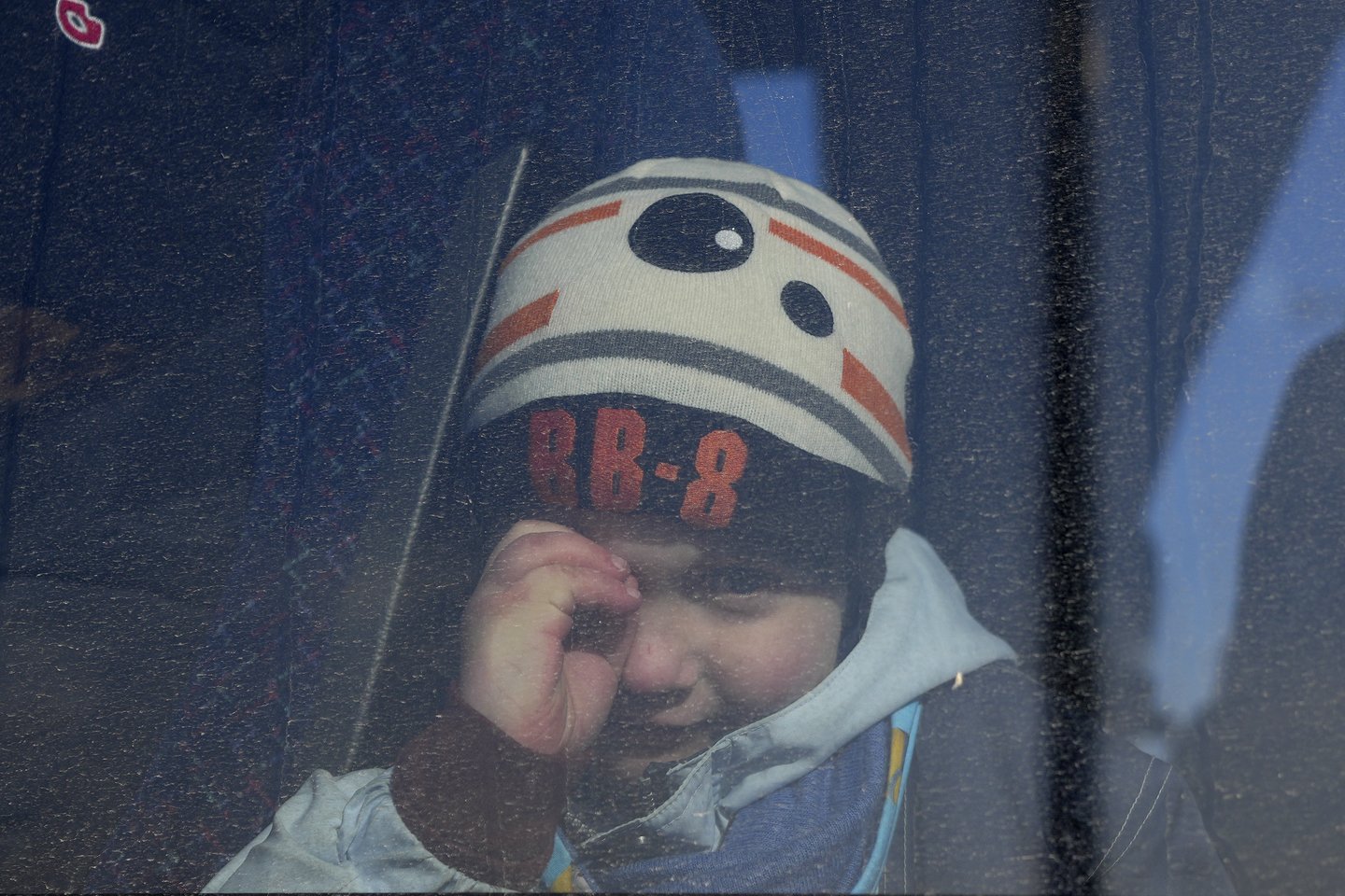 Berniukas žiūri pro autobuso langą. Dalis ukrainiečių priversti bėgti iš namų.<br>AP/Scanpix nuotr.