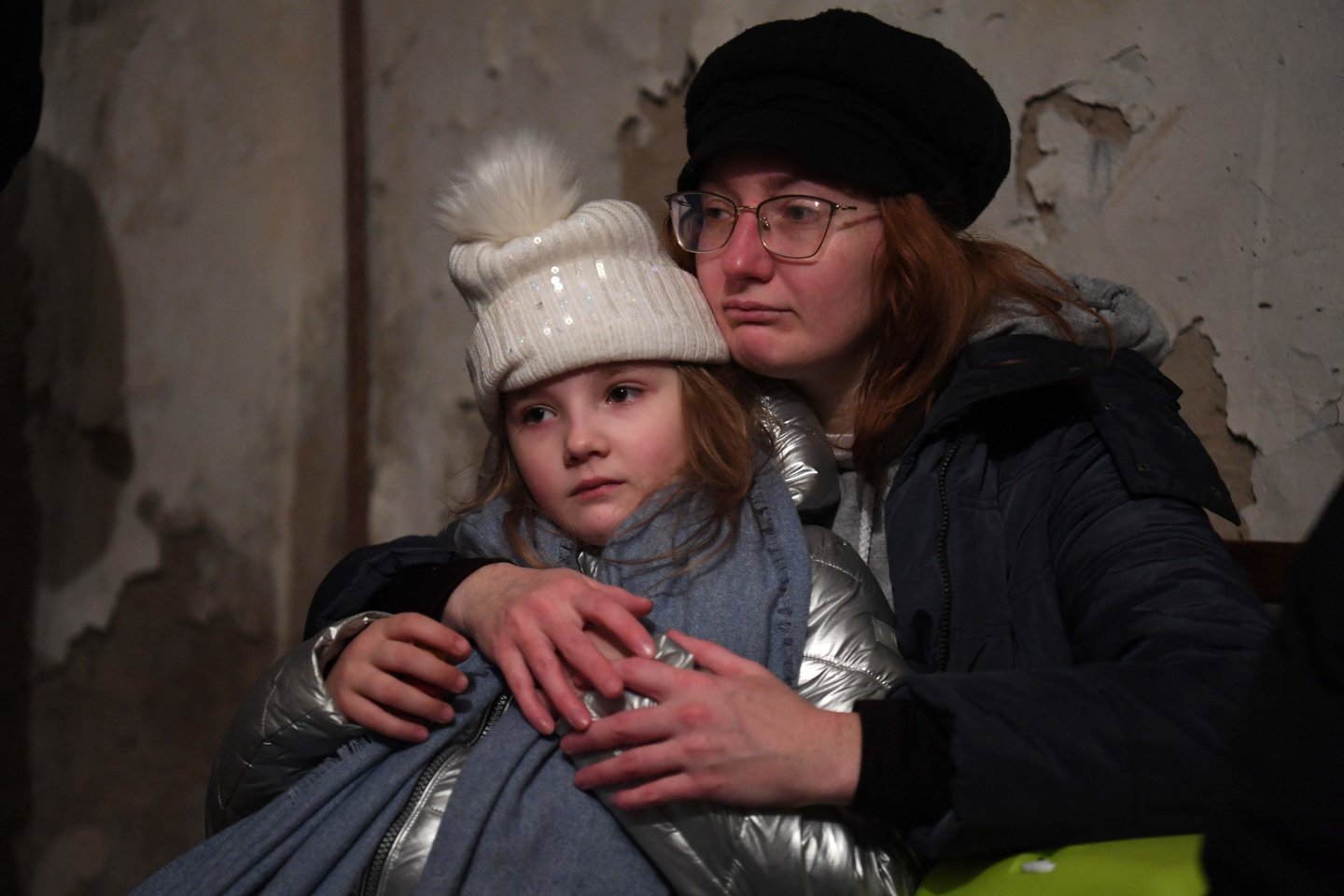 H.Tarasova apkabinusi savo dukrą. Abi slepiasi požeminėje slėptuvėje, aidint sirenai dėl pavojaus. Kijevas.<br>AFP/Scanpix nuotr.