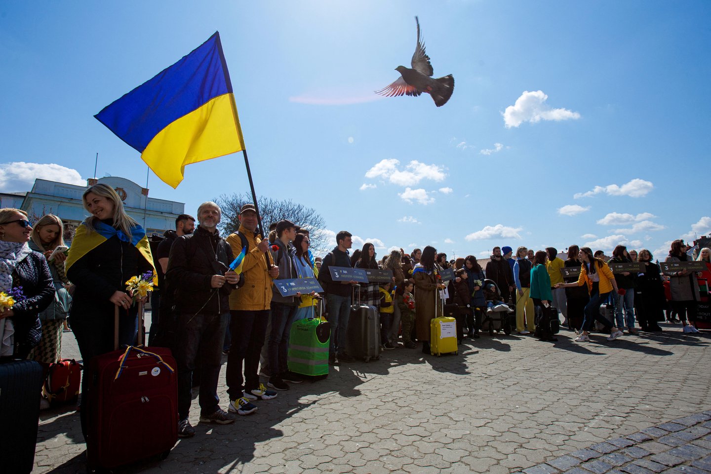 Ukrainiečiai su lagaminais dalyvauja renginyje, kuriuo siekiama atkreipti dėmesį į žmonių, dėl Rusijos invazijos palikusių savo namus, padėtį.<br> Reuters/Scanpix nuotr.