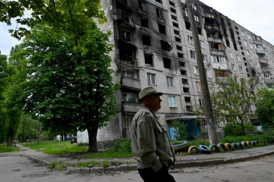 Karas Ukrainoje. Vyras eina pro apgadintą pastatą Charkove 2022 m. gegužės 21 d.