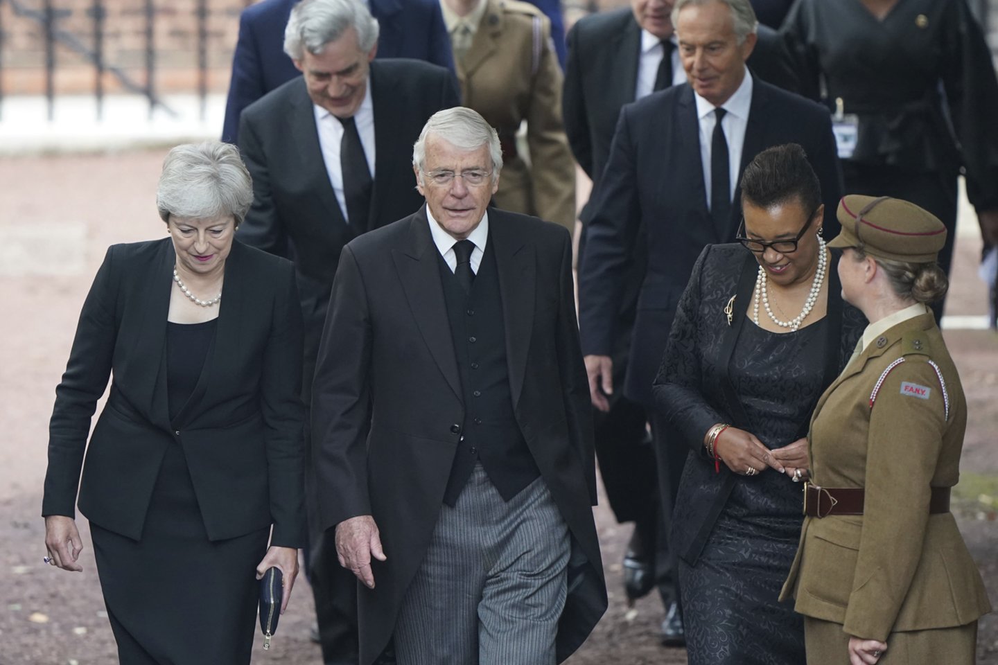 Buvę Didžiosios Britanijos ministrai pirmininkai Theresa May (priekyje kairėje), Johnas Majoras (centre) ir baronienė Scotland atvyksta į Stojimo tarybos ceremoniją Švento Jokūbo rūmuose Londone.<br>AP/Scanpix nuotr.