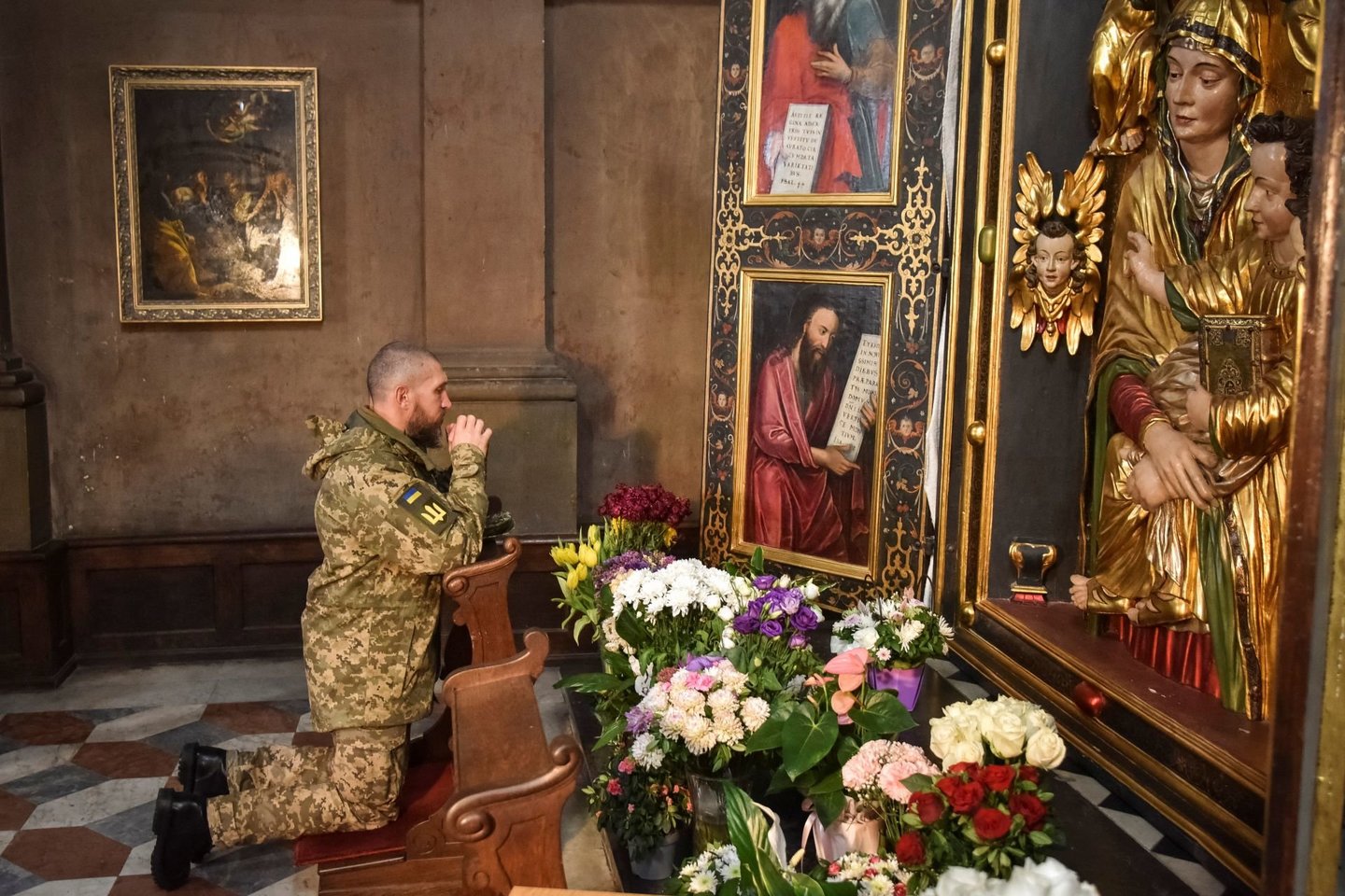 Ukrainos karys meldžiasi per savo ginklo brolių, neseniai žuvusių Lvive, laidotuves.<br> Reuters / Scanpix nuotr.