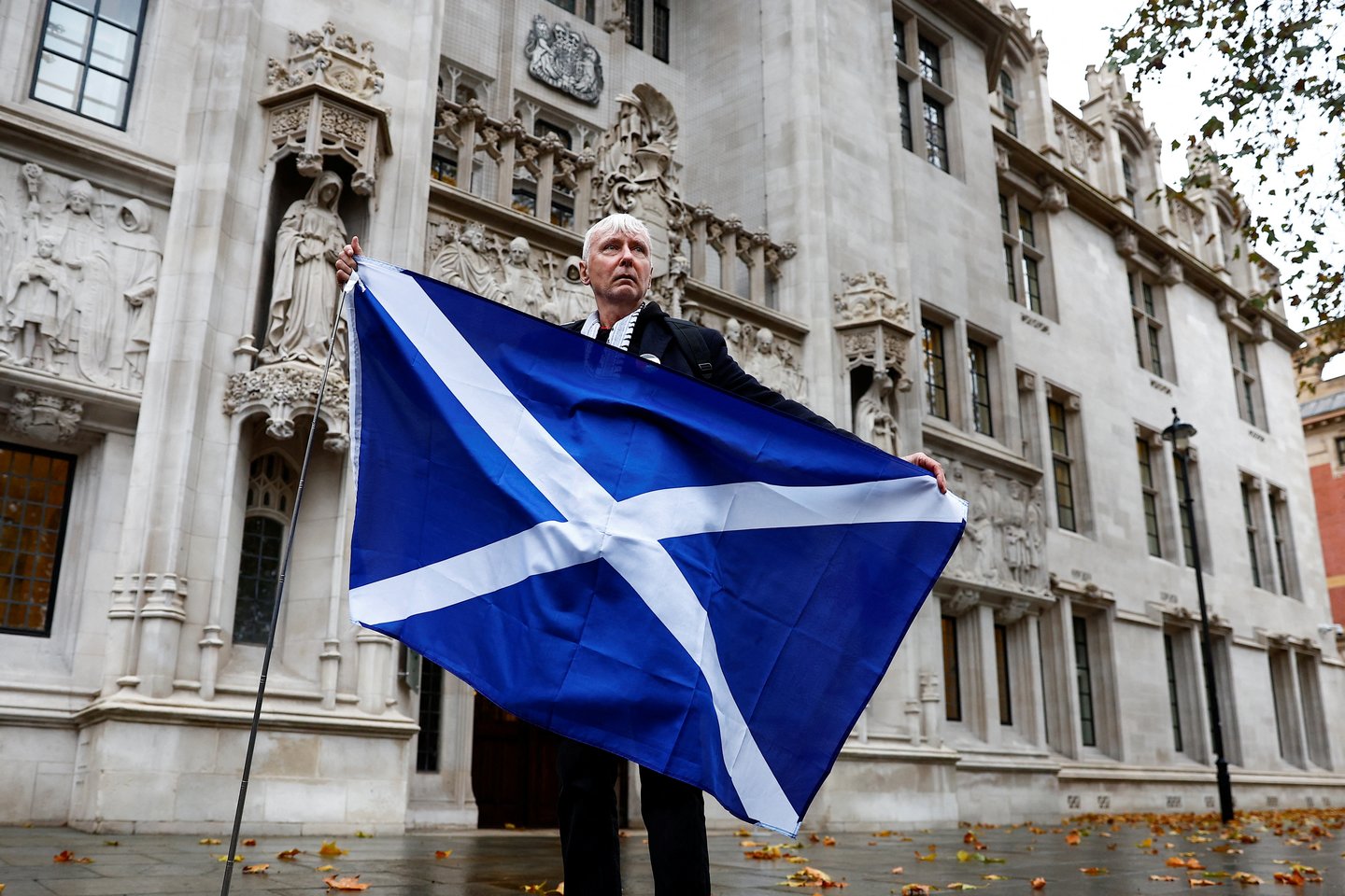 Už Škotijos nepriklausomybę pasisakantis kampanijos dalyvis pozuoja su Škotijos vėliava prie Jungtinės Karalystės Aukščiausiojo Teismo.<br>Reuters/Scanpix nuotr.