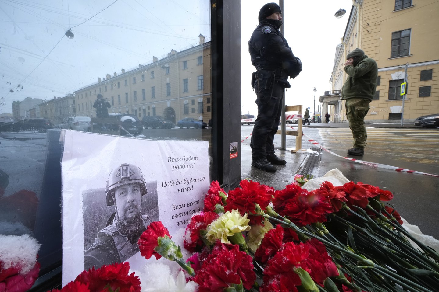 Gėlės ir plakatas su tinklaraštininko Vladleno Tatarskio nuotrauka prie sprogimo vietos kavinėje „Street Bar“ Sankt Peterburge.<br>AP/Scanpix nuotr.