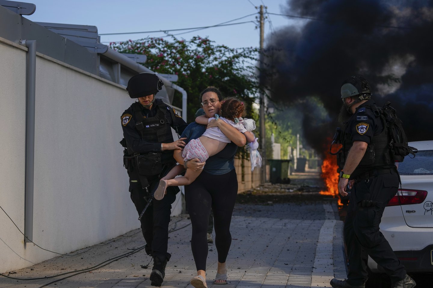  Moteris su vaiku ant rankų bėga per teroristų išpuolį Izraelyje.<br> AP/Scanpix nuotr.