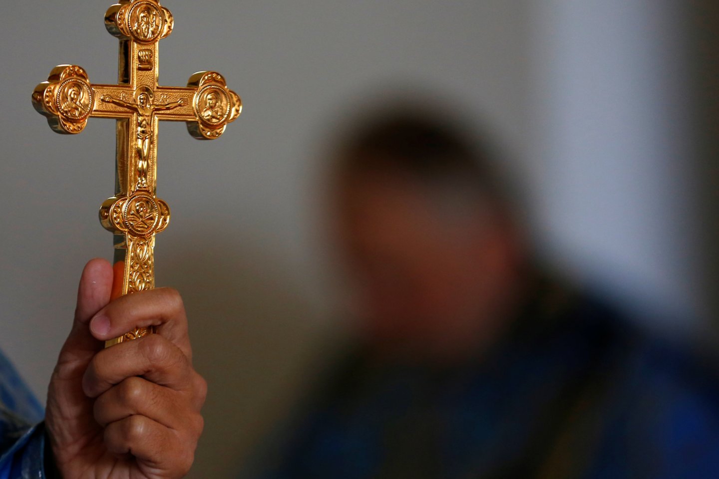 Rusų stačiatikių bažnyčios kunigas laiko kryžių per mišias mažoje katalikų koplyčioje.<br>Reuters/Scanpix nuotr.