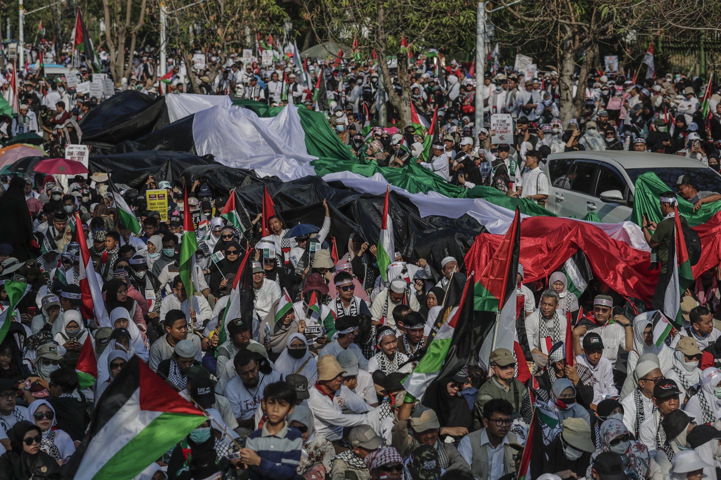 Žmonės laiko milžinišką Palestinos vėliavą per solidarumo su palestiniečiais mitingą prie JAV ambasados Džakartoje, Indonezijoje. Spalio 28 d. tūkstančiai žmonių surengė mitingą, ragindami pasaulio lyderius sustabdyti smurtą Gazos ruože.<br>EPA-ELTA nuotr.