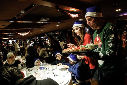 Savanoriai dalino patiekalus svečiams per ne pelno siekiančios asociacijos „Secours Catholique“ organizuojamą Solidarumo Kalėdų vakarienę šešiose baržose ant Senos upės kranto Paryžiuje, Prancūzijoje, gruodžio 24 d. Renginį, pavadintą „Fraternoel“ („Broliškos Kalėdos“), „Secours Catholique“ organizuoja visoje Prancūzijoje. Tikimasi, kad renginyje dalyvaus daugiau kaip 600 žmonių, atsidūrusių sunkioje padėtyje.<br>EPA-ELTA nuotr.